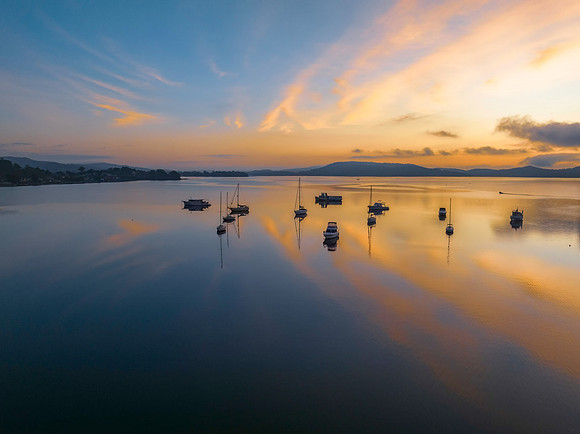 Sunrise over the water with fog, boats, clouds and reflections