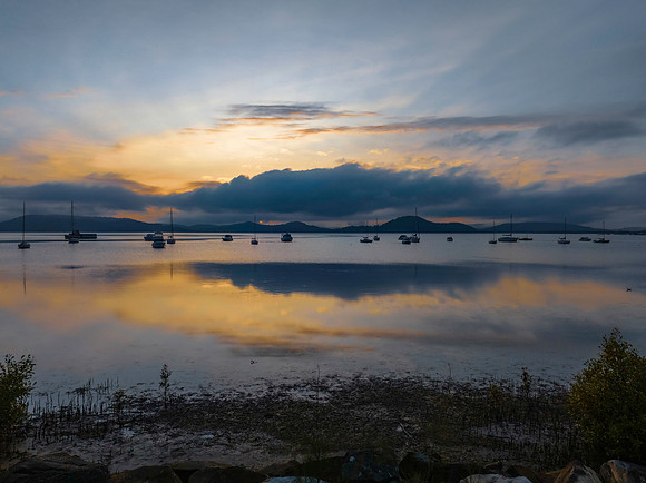 Sunrise over the water with fog, boats, clouds and reflections