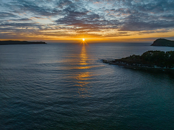 Aerial sunrise seascape with calm seas and a mix of low and medi