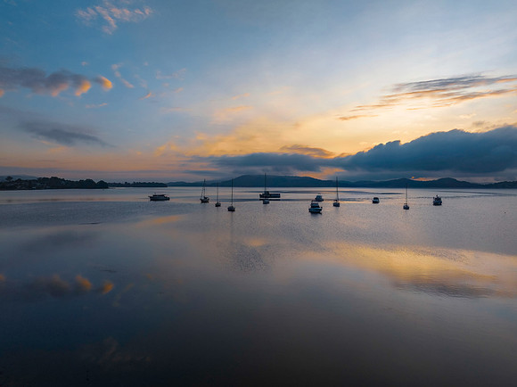 Sunrise over the water with fog, boats, clouds and reflections