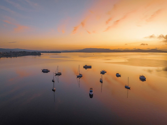 Sunrise over the water with fog, boats, clouds and reflections