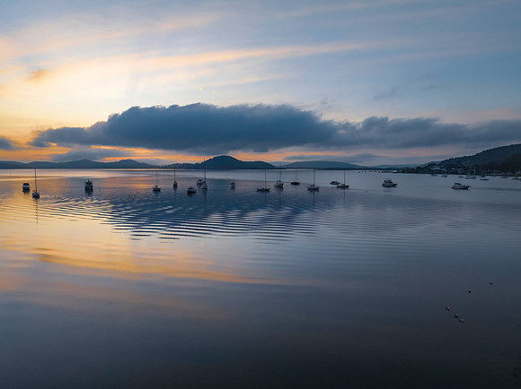 Sunrise over the water with fog, boats, clouds and reflections