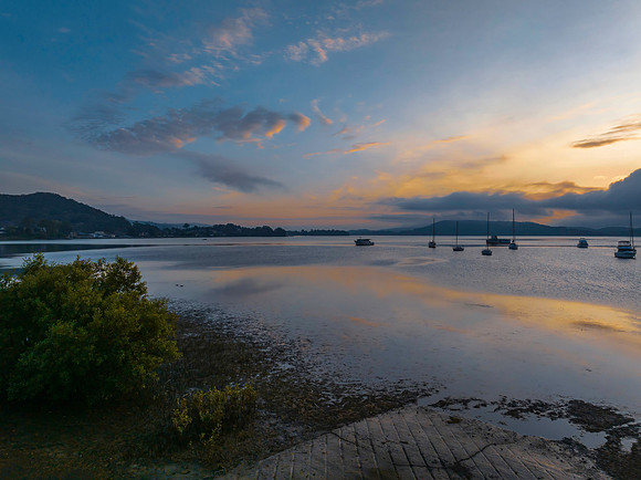Sunrise over the water with fog, boats, clouds and reflections