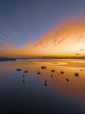 Sunrise over the water with fog, boats, clouds and reflections