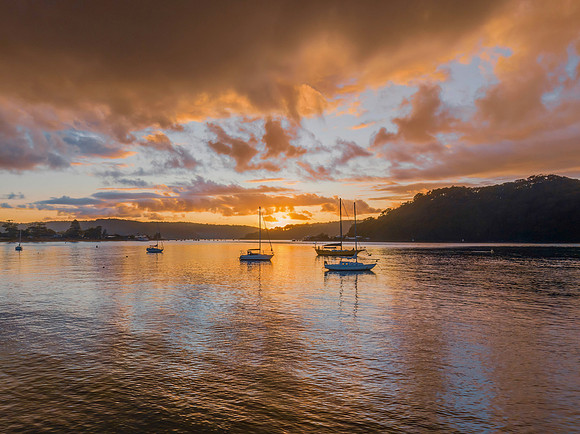 Aerial sunrise waterscape with boats and rain clouds