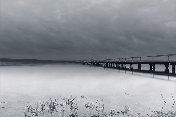 Rainy day sunrise waterscape with wharf in monochrome