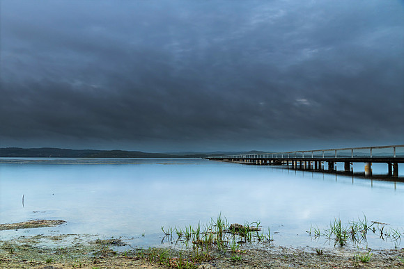 Rainy day sunrise waterscape with wharf