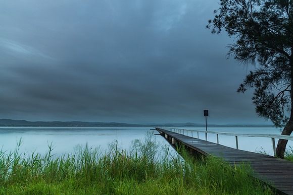 Rainy day sunrise waterscape with wharf
