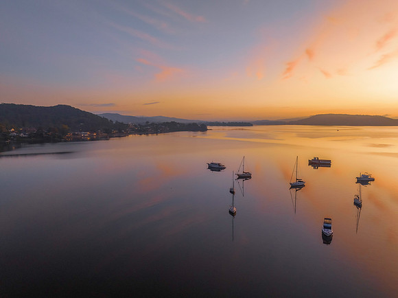 Sunrise over the water with fog, boats, clouds and reflections