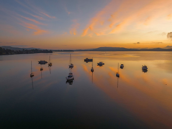 Sunrise over the water with fog, boats, clouds and reflections