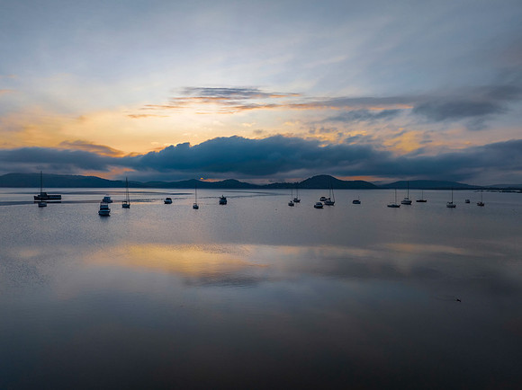 Sunrise over the water with fog, boats, clouds and reflections
