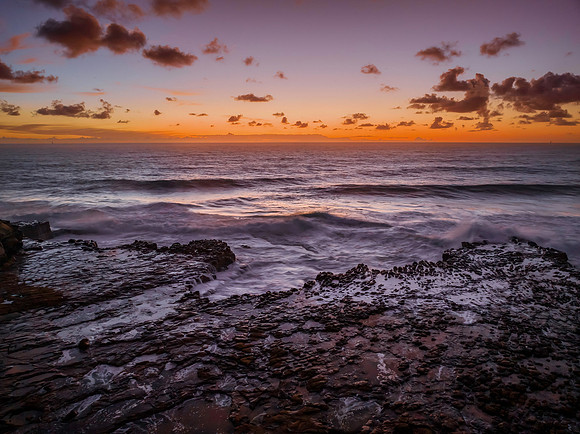 Surfs up sunrise at the seaside with scattered clouds