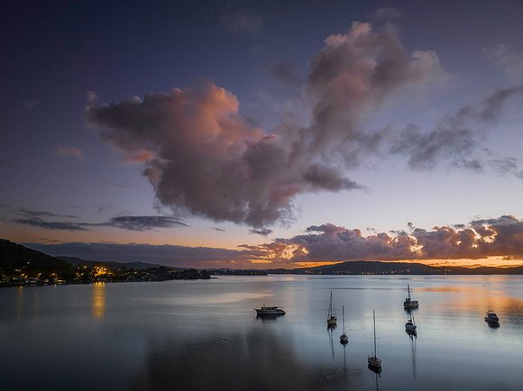 Aerial sunrise waterscape with boats, clouds and reflections
