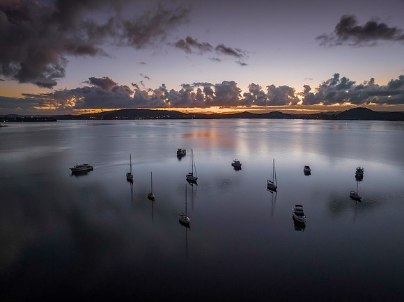 Aerial sunrise waterscape with boats, clouds and reflections