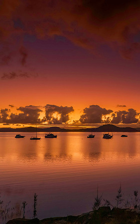 Aerial sunrise waterscape with boats, clouds and reflections