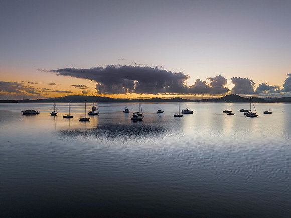 Aerial sunrise waterscape with boats, clouds and reflections