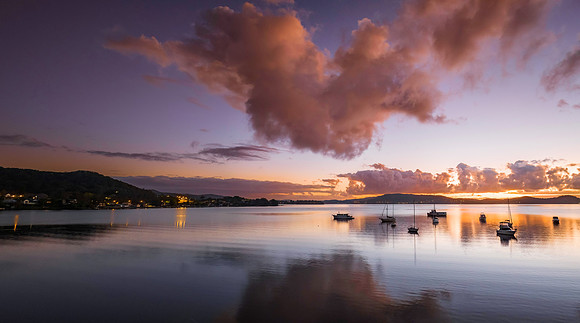 Aerial sunrise waterscape panorama with boats, clouds and reflec