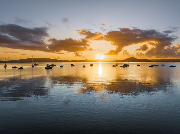 Aerial sunrise waterscape with boats, clouds and reflections