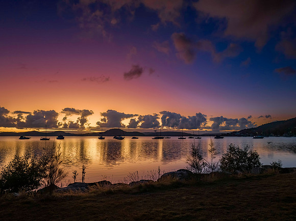 Aerial sunrise waterscape with boats, clouds and reflections