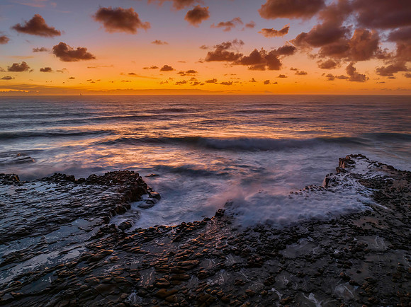 Surfs up sunrise at the seaside with scattered clouds
