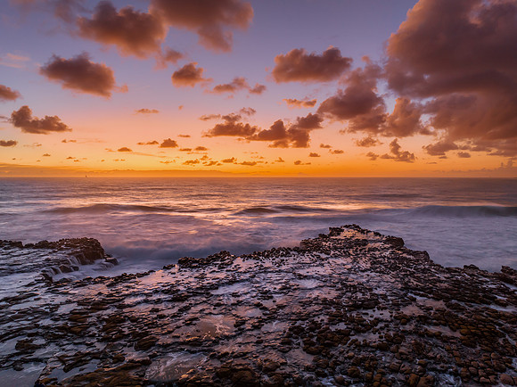 Surfs up sunrise at the seaside with scattered clouds