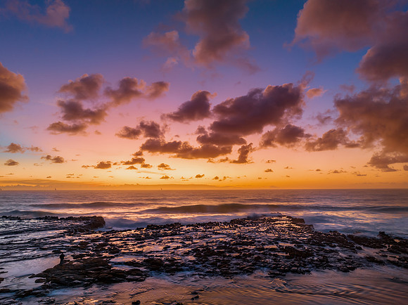Surfs up sunrise at the seaside with scattered clouds