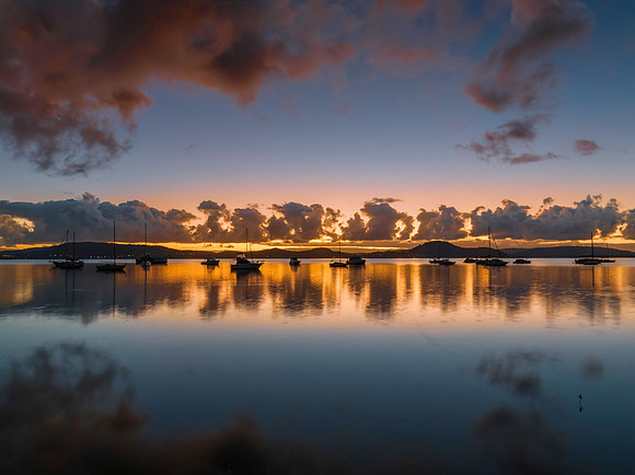Aerial sunrise waterscape with boats, clouds and reflections