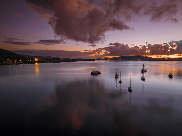 Aerial sunrise waterscape with boats, clouds and reflections