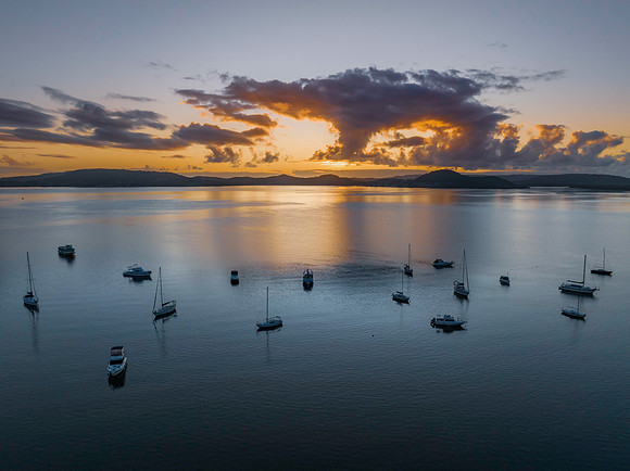 Aerial sunrise waterscape with boats, clouds and reflections