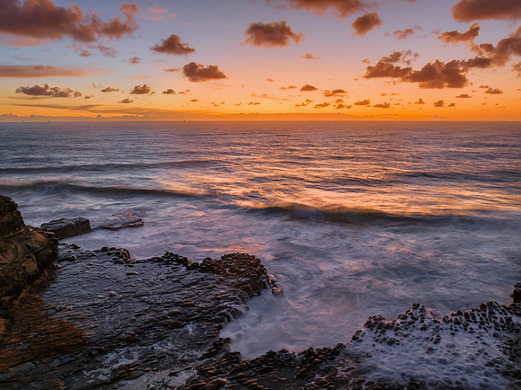 Surfs up sunrise at the seaside with scattered clouds