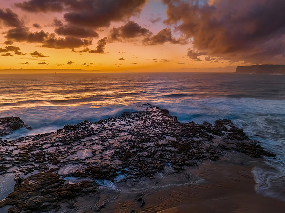 Surfs up sunrise at the seaside with scattered clouds