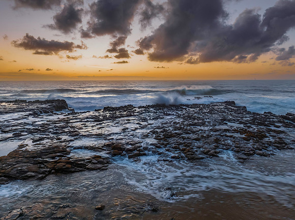 Surfs up sunrise at the seaside with scattered clouds