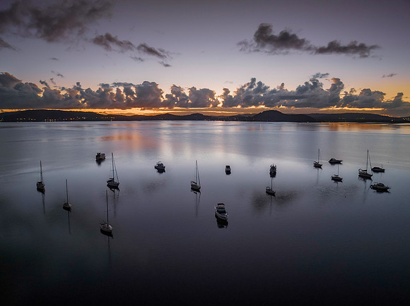 Aerial sunrise waterscape with boats, clouds and reflections