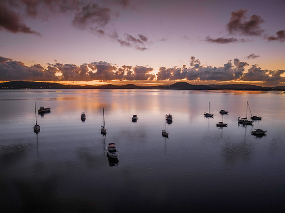 Aerial sunrise waterscape with boats, clouds and reflections