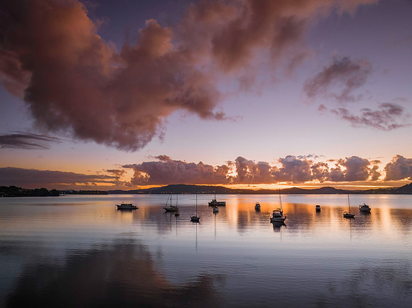 Aerial sunrise waterscape with boats, clouds and reflections
