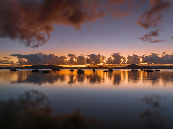 Aerial sunrise waterscape with boats, clouds and reflections