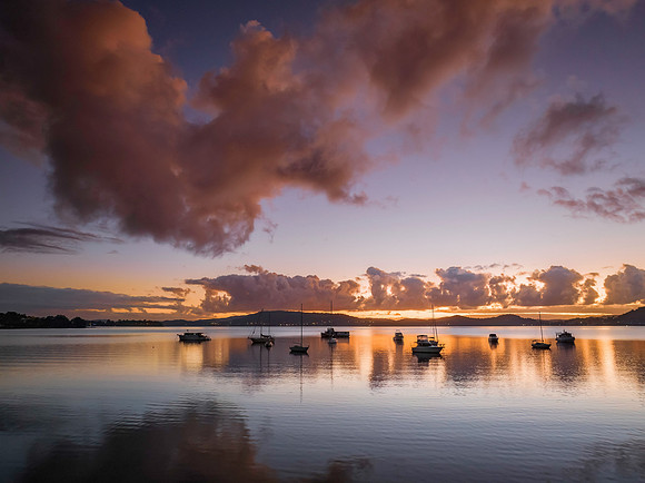 Aerial sunrise waterscape with boats, clouds and reflections