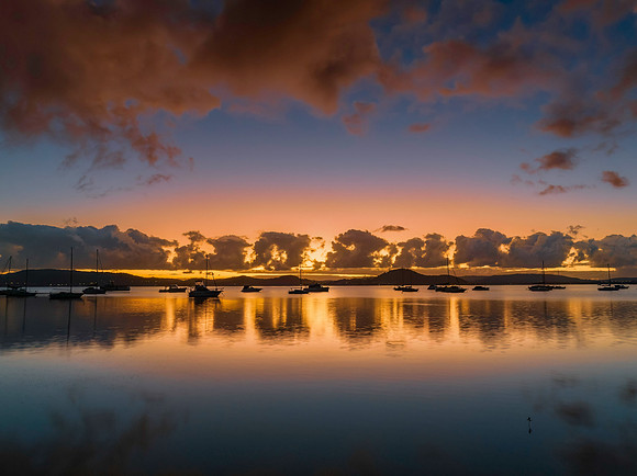 Aerial sunrise waterscape with boats, clouds and reflections