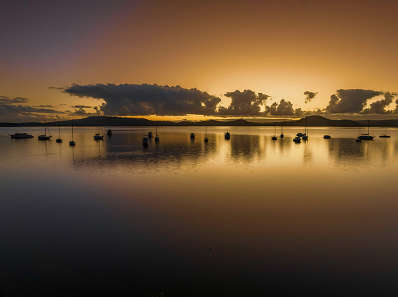 Aerial sunrise waterscape with boats, clouds and reflections