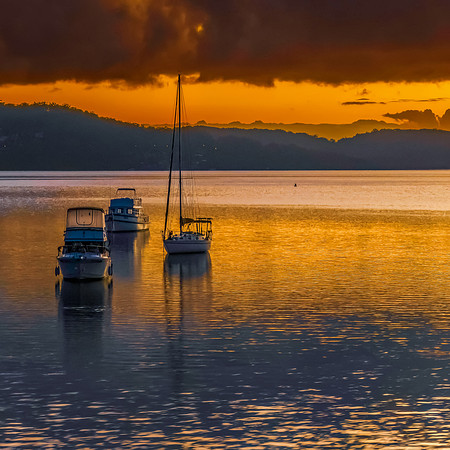 Golden hour sunrise waterscape with boats and mountains
