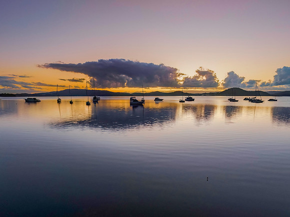 Aerial sunrise waterscape with boats, clouds and reflections