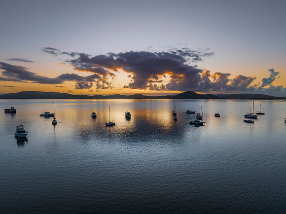 Aerial sunrise waterscape with boats, clouds and reflections