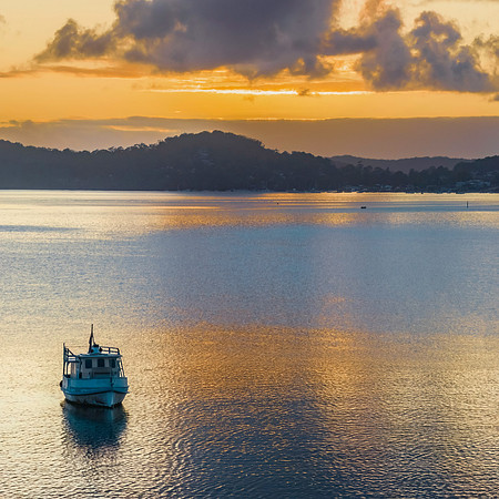 Aerial sunrise waterscape with a boat and clouds