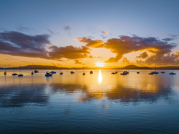 Aerial sunrise waterscape with boats, clouds and the sun