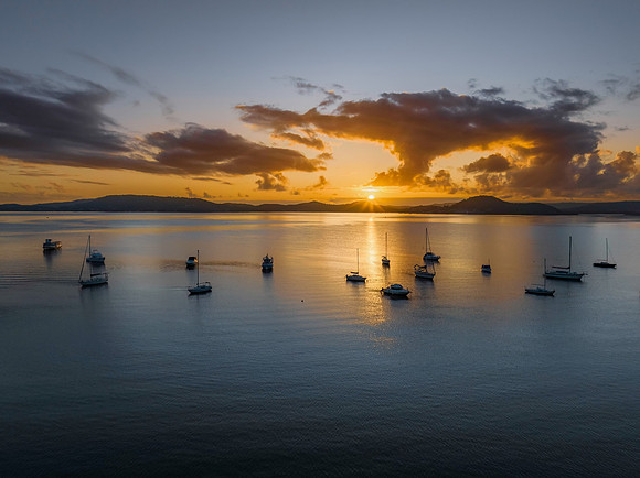 Aerial sunrise waterscape with boats, clouds and reflections