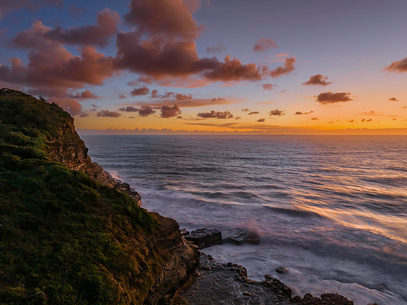 Surfs up sunrise at the seaside with scattered clouds