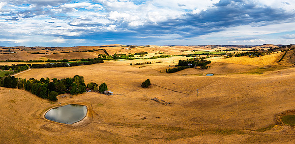 Golden Hour Panorama with Cloudy Skies Over Farmland