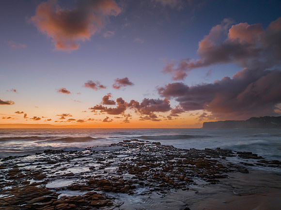 Surfs up sunrise at the seaside with scattered clouds