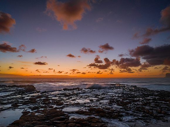Surfs up sunrise at the seaside with scattered clouds