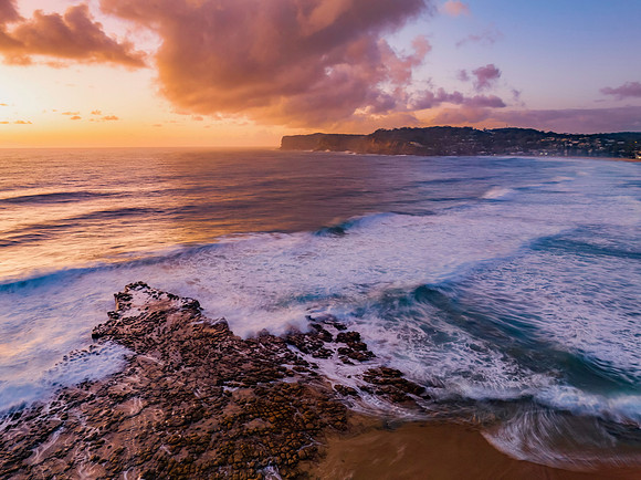 Surfs up sunrise at the seaside with scattered clouds